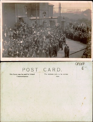 Large crowd of men in formal dress outside stone gated building