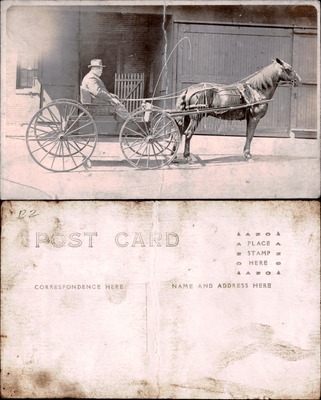 Man in horse-drawn buggy in front of brick building