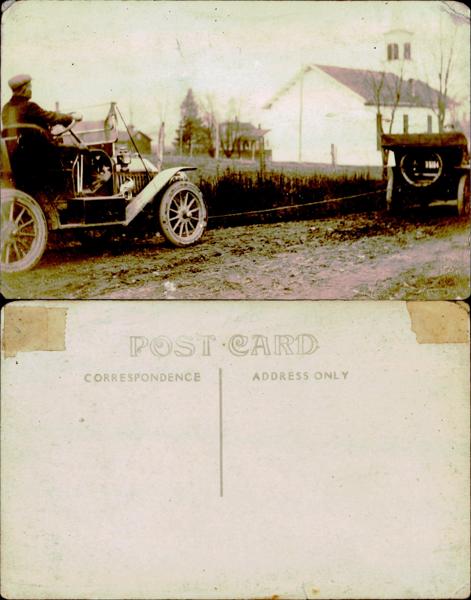 Vintage automobile on a muddy road with a church